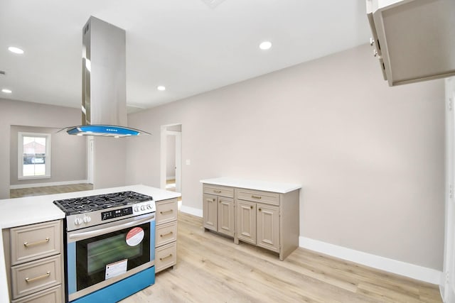 kitchen featuring gas range, wall chimney exhaust hood, and light hardwood / wood-style floors