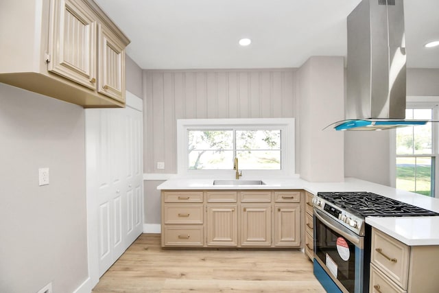 kitchen with stainless steel gas range oven, sink, light brown cabinets, and island exhaust hood