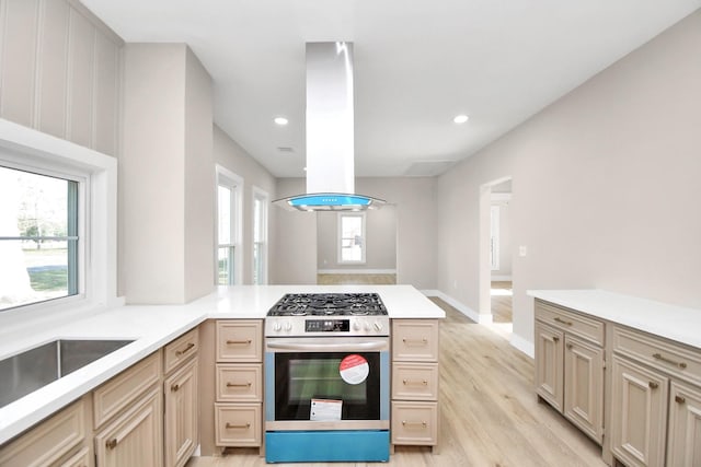 kitchen featuring plenty of natural light, light hardwood / wood-style floors, island exhaust hood, and gas range