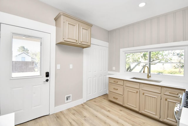 kitchen with range, light wood-type flooring, light brown cabinets, and sink