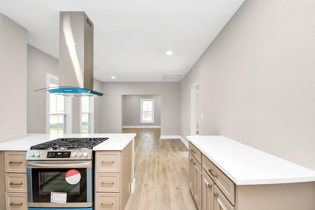 kitchen featuring gas range, a kitchen island, light brown cabinetry, light hardwood / wood-style floors, and island exhaust hood