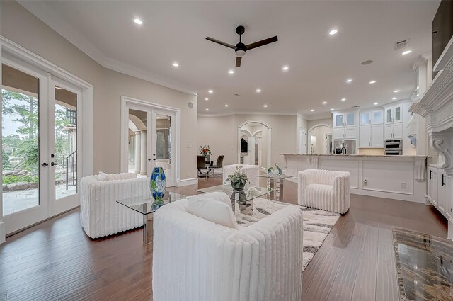 living room with dark wood-type flooring, ceiling fan, french doors, and ornamental molding