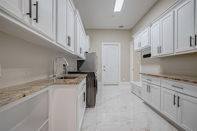 kitchen featuring light stone countertops, visible vents, a sink, white cabinets, and marble finish floor