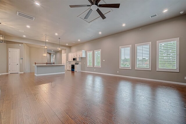 unfurnished living room with ceiling fan with notable chandelier and light hardwood / wood-style flooring