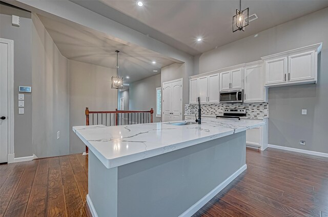 kitchen with decorative light fixtures, stainless steel appliances, white cabinets, and a large island with sink