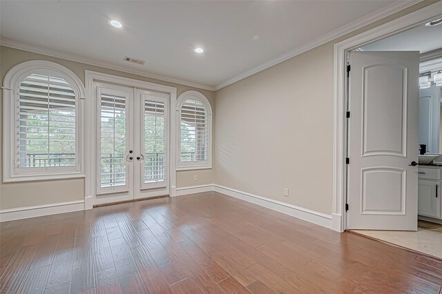 unfurnished room with ornamental molding, light wood-type flooring, and french doors