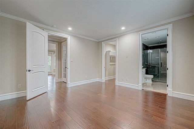 spare room with baseboards, wood finished floors, and ornamental molding