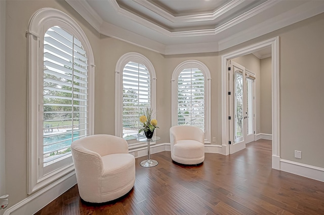 living area with dark wood-type flooring, a raised ceiling, and crown molding