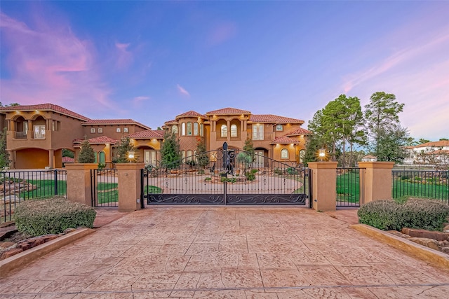 gate at dusk featuring a fenced front yard