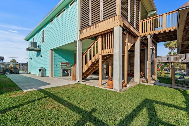 rear view of house featuring a lawn, a patio area, and a wooden deck