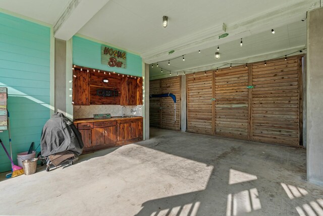 interior space featuring backsplash, wood walls, sink, and concrete flooring