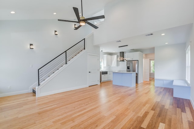 unfurnished living room featuring light hardwood / wood-style floors, high vaulted ceiling, and ceiling fan