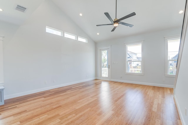 empty room featuring ceiling fan, light hardwood / wood-style flooring, high vaulted ceiling, and plenty of natural light