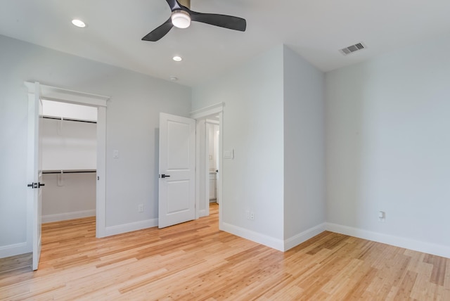 unfurnished bedroom featuring a spacious closet, ceiling fan, light wood-type flooring, and a closet