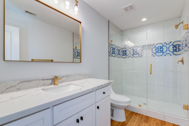 bathroom featuring vanity, hardwood / wood-style flooring, toilet, and an enclosed shower