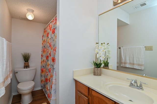 bathroom with a shower with curtain, vanity, a textured ceiling, hardwood / wood-style floors, and toilet