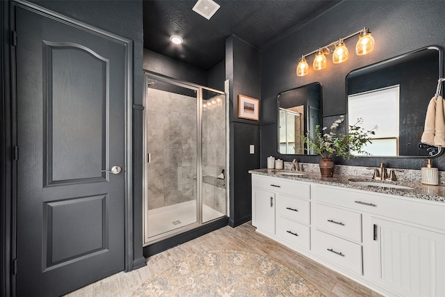 bathroom with hardwood / wood-style flooring, vanity, and walk in shower