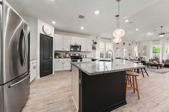 kitchen featuring white cabinetry, an island with sink, decorative light fixtures, and appliances with stainless steel finishes