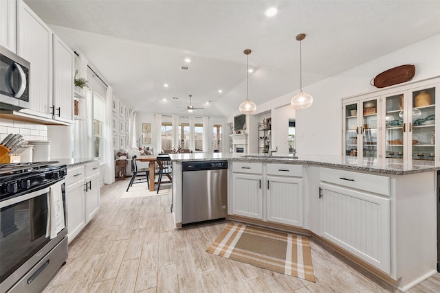 kitchen with lofted ceiling, hanging light fixtures, ceiling fan, white cabinetry, and stainless steel appliances