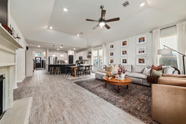 living room featuring a premium fireplace, plenty of natural light, ceiling fan, and lofted ceiling