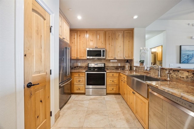 kitchen with dark stone countertops, decorative backsplash, sink, and stainless steel appliances