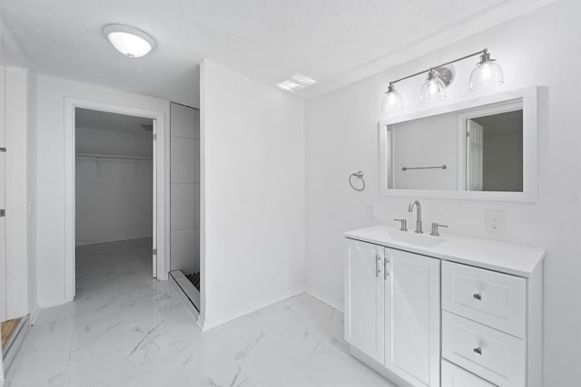 bathroom with a textured ceiling, vanity, and walk in shower