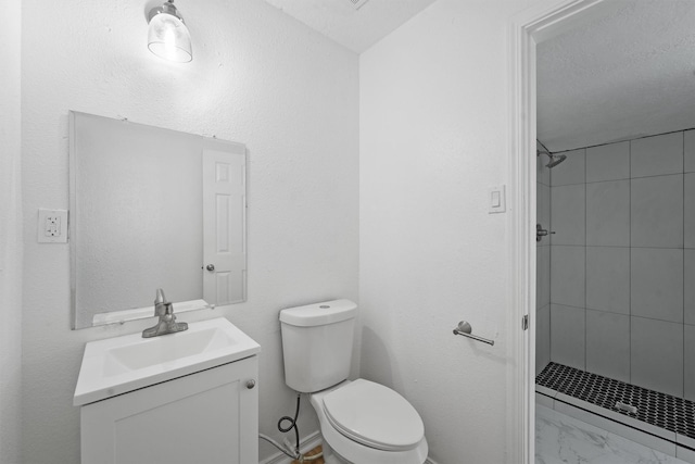 bathroom featuring vanity, a tile shower, a textured ceiling, and toilet