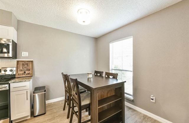 dining space with a textured ceiling and light hardwood / wood-style flooring