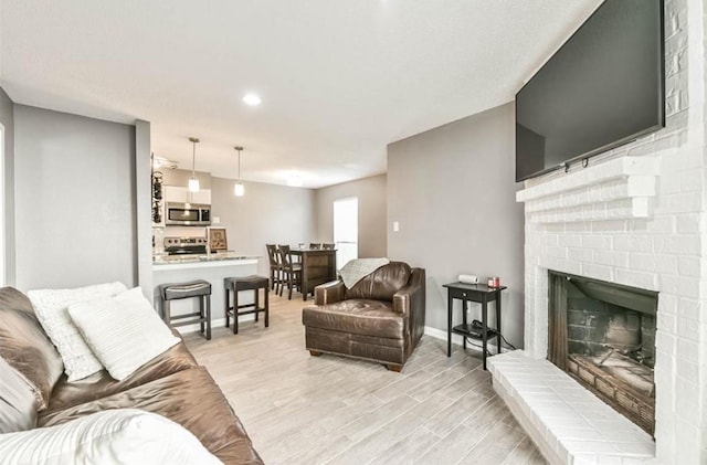 living room featuring light hardwood / wood-style flooring and a brick fireplace