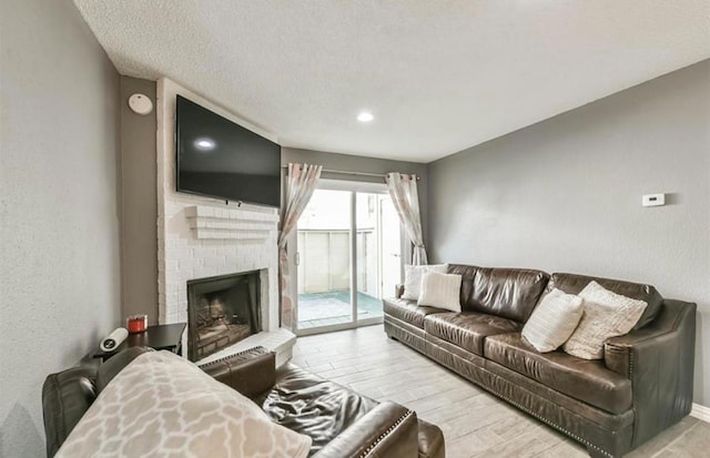 living room featuring a fireplace, light hardwood / wood-style flooring, and a textured ceiling