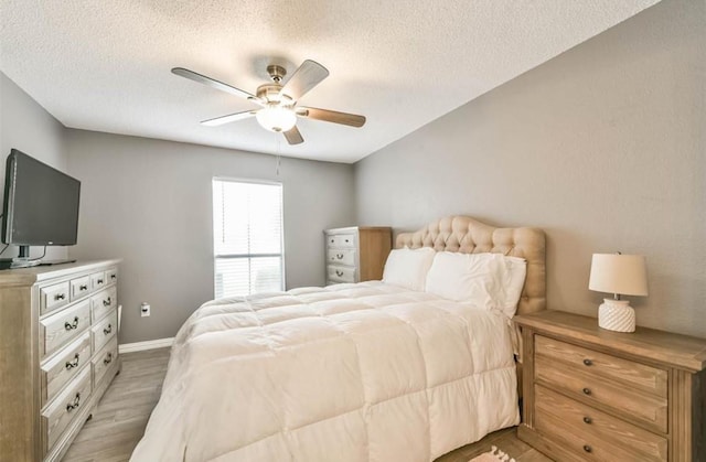 bedroom with a textured ceiling, light hardwood / wood-style floors, and ceiling fan