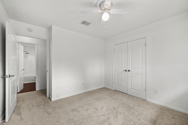 unfurnished bedroom featuring light carpet, a textured ceiling, a closet, and ceiling fan