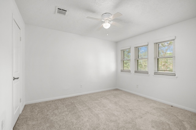 spare room featuring light carpet, ceiling fan, and a textured ceiling