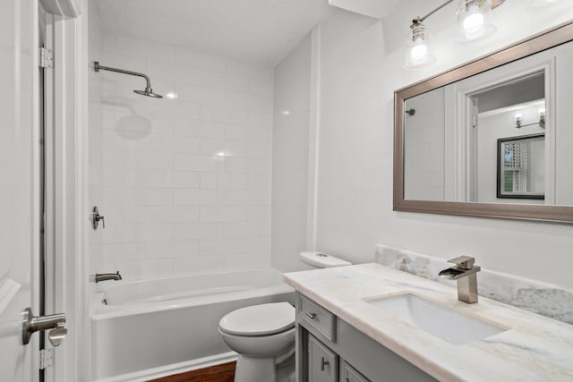 full bathroom featuring hardwood / wood-style floors, vanity, tiled shower / bath combo, and toilet