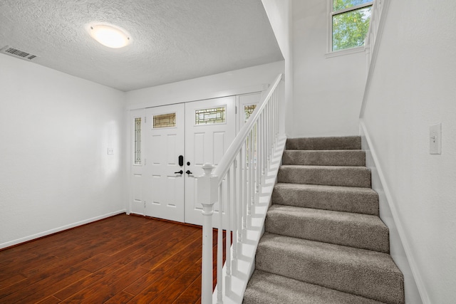 entrance foyer featuring a textured ceiling and dark wood-type flooring