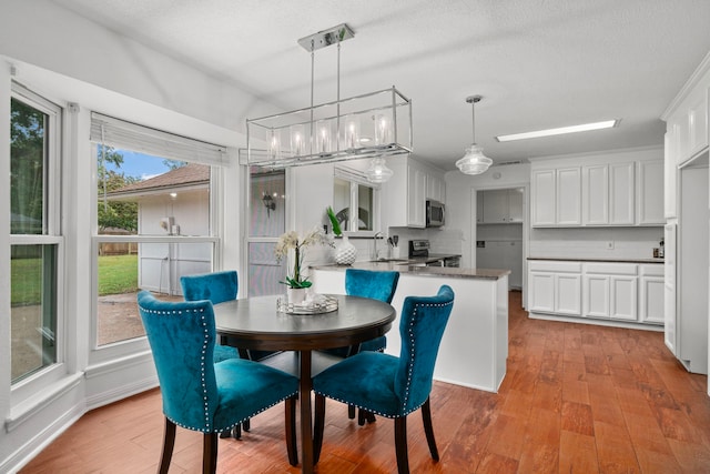 dining space with a wealth of natural light, sink, light hardwood / wood-style floors, and a textured ceiling