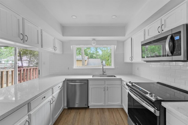 kitchen featuring stainless steel appliances, light hardwood / wood-style flooring, white cabinetry, and sink