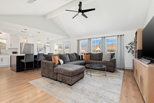 living room featuring vaulted ceiling with beams, light hardwood / wood-style floors, and ceiling fan