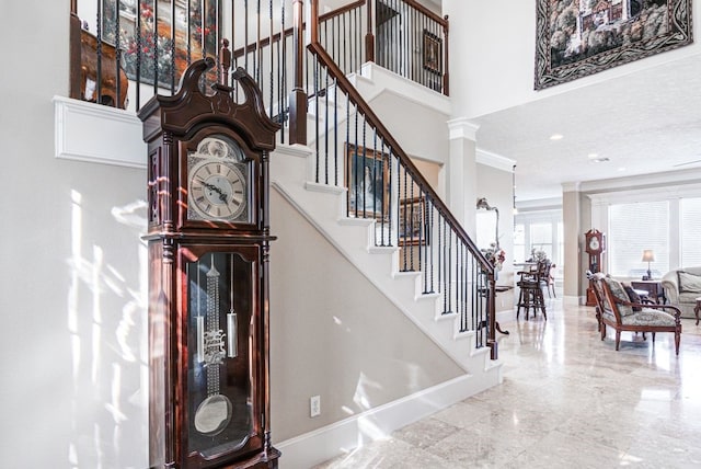 stairway featuring ornate columns and a towering ceiling