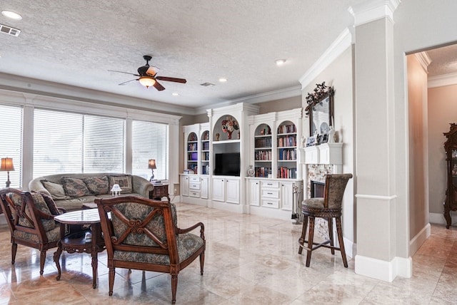 living room featuring a tile fireplace, crown molding, ornate columns, and a textured ceiling