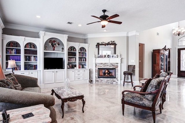 living room with crown molding, built in features, a stone fireplace, ceiling fan with notable chandelier, and a textured ceiling