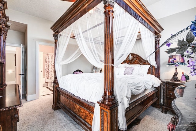 carpeted bedroom featuring a textured ceiling and ensuite bath