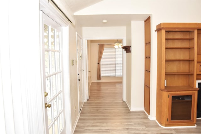 hall with vaulted ceiling and light wood-type flooring