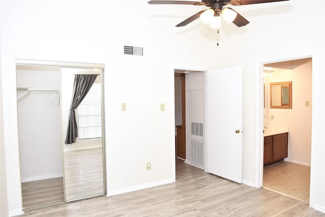 unfurnished bedroom with connected bathroom, a closet, light hardwood / wood-style flooring, and ceiling fan