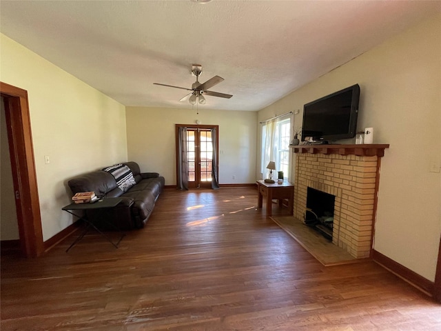 living room with ceiling fan, dark hardwood / wood-style flooring, a fireplace, and french doors