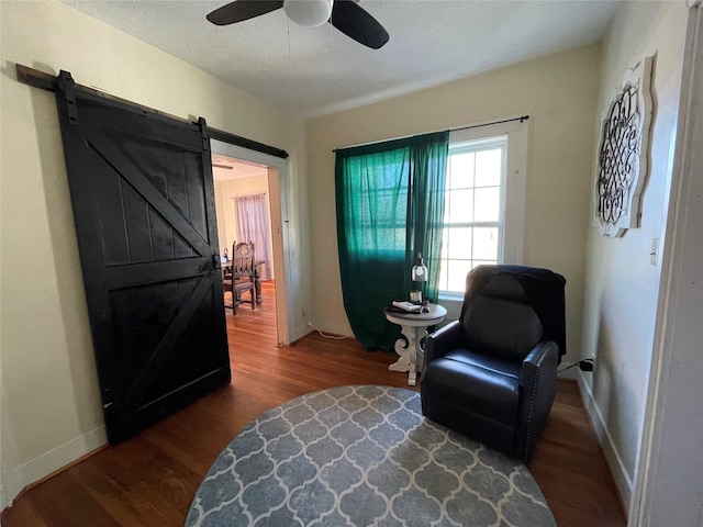 sitting room with hardwood / wood-style floors, a barn door, a textured ceiling, and ceiling fan