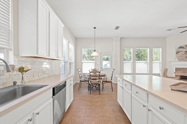 kitchen featuring stainless steel dishwasher, sink, pendant lighting, light tile patterned floors, and white cabinetry