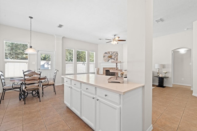 kitchen with ceiling fan, light tile patterned floors, decorative light fixtures, white cabinets, and plenty of natural light