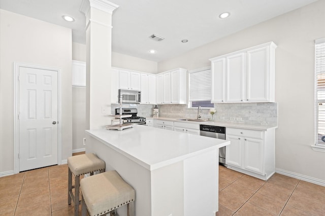 kitchen with a breakfast bar, white cabinetry, light tile patterned floors, and appliances with stainless steel finishes