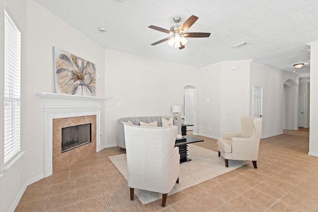 living room featuring light tile patterned flooring, ceiling fan, a healthy amount of sunlight, and a tiled fireplace